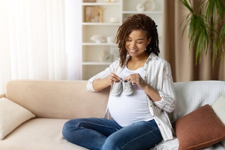 hymyileva odottava aiti sylissaan vauvatossut