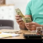 ihminen-laskee-rahaa-poydan-aaressa