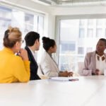 ihmisia-kokoushuoneessa-keskustelemassa-poydan-aaressa