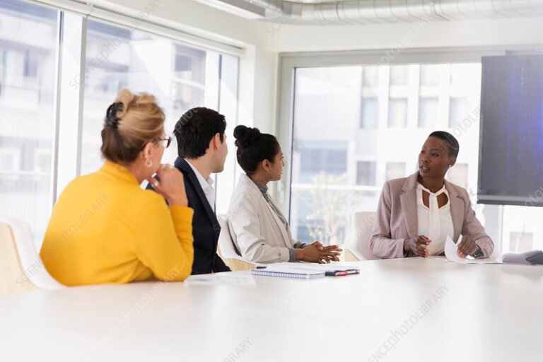 ihmisia kokoushuoneessa keskustelemassa poydan aaressa