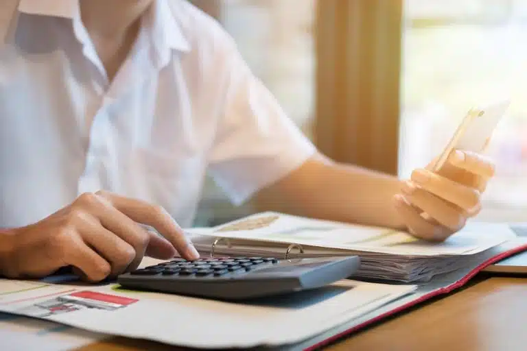 Miten Vuosikorko Lasketaan Säästö- tai Lainalaskurissa 2 kateva henkilo kayttaa laskinta poydalla