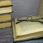 vanha-kirjapino-ja-lukulasit-poydalla